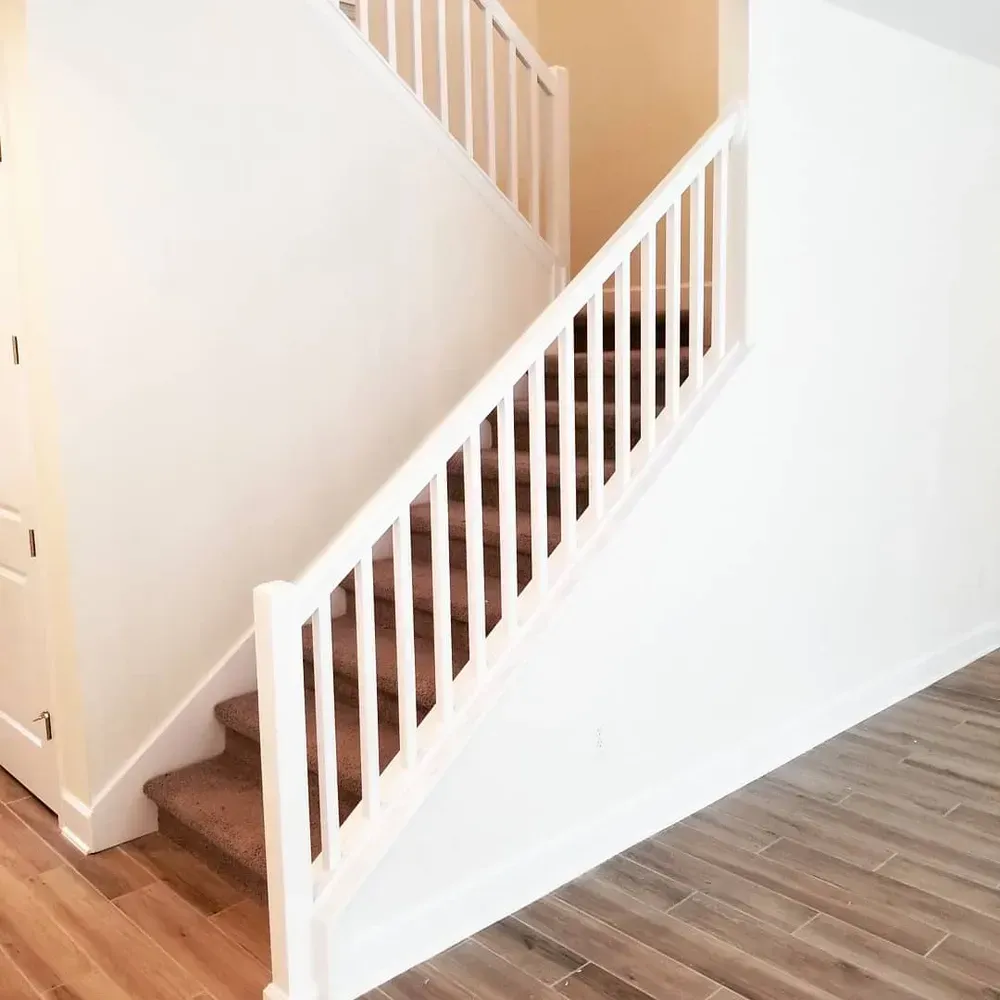 A staircase with a white railing and a wooden floor