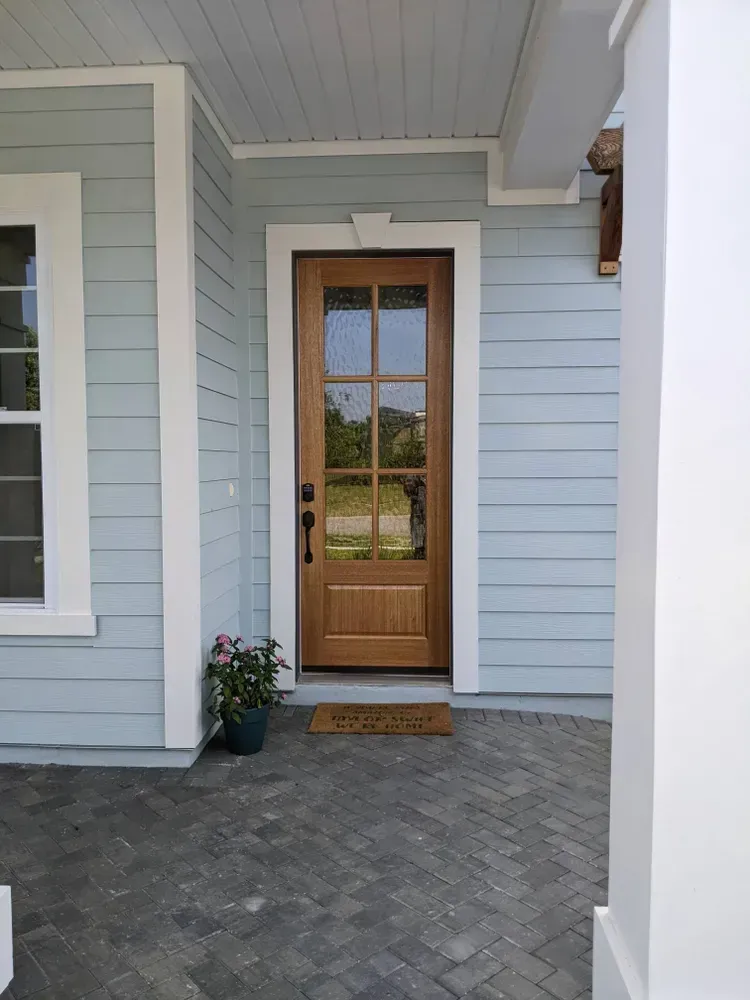 The front door of a house with blue siding and a wooden door