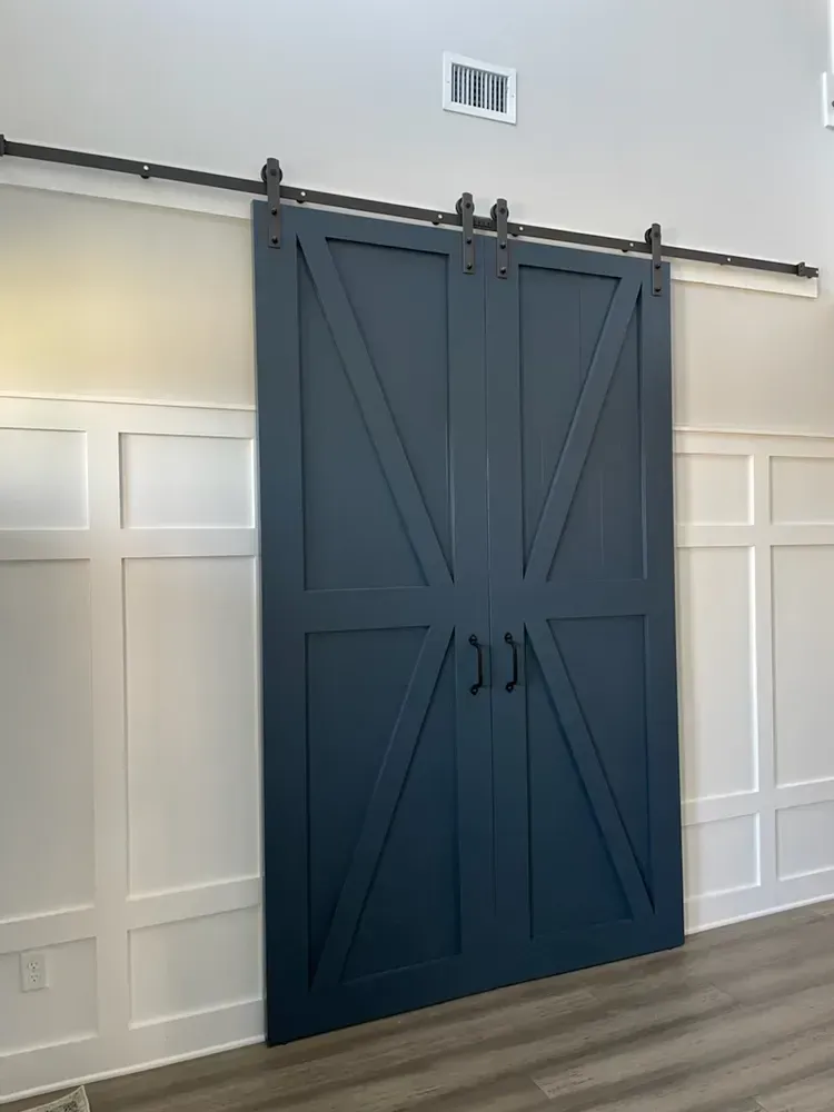 A blue barn door is hanging on a white wall in a room.