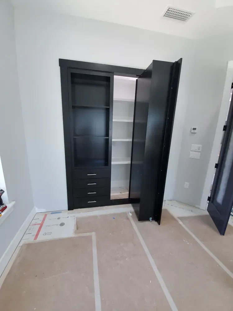 A room with a black cabinet and shelves in it