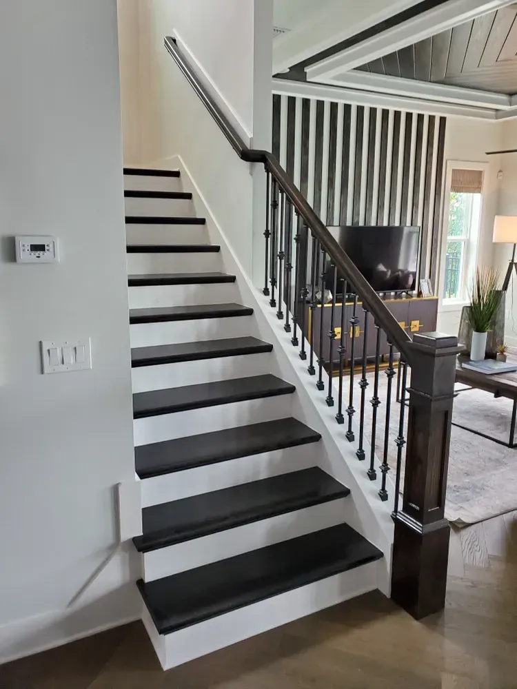 A white staircase with black steps and a black railing in a living room.