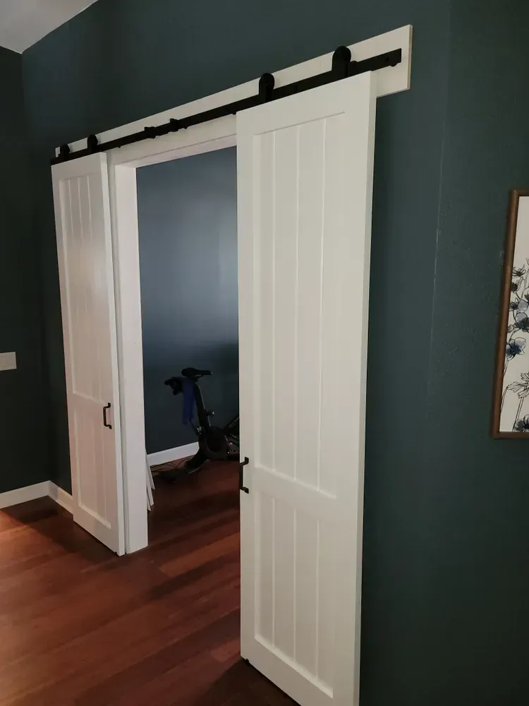 A sliding barn door is open to a room with a bicycle in the background.