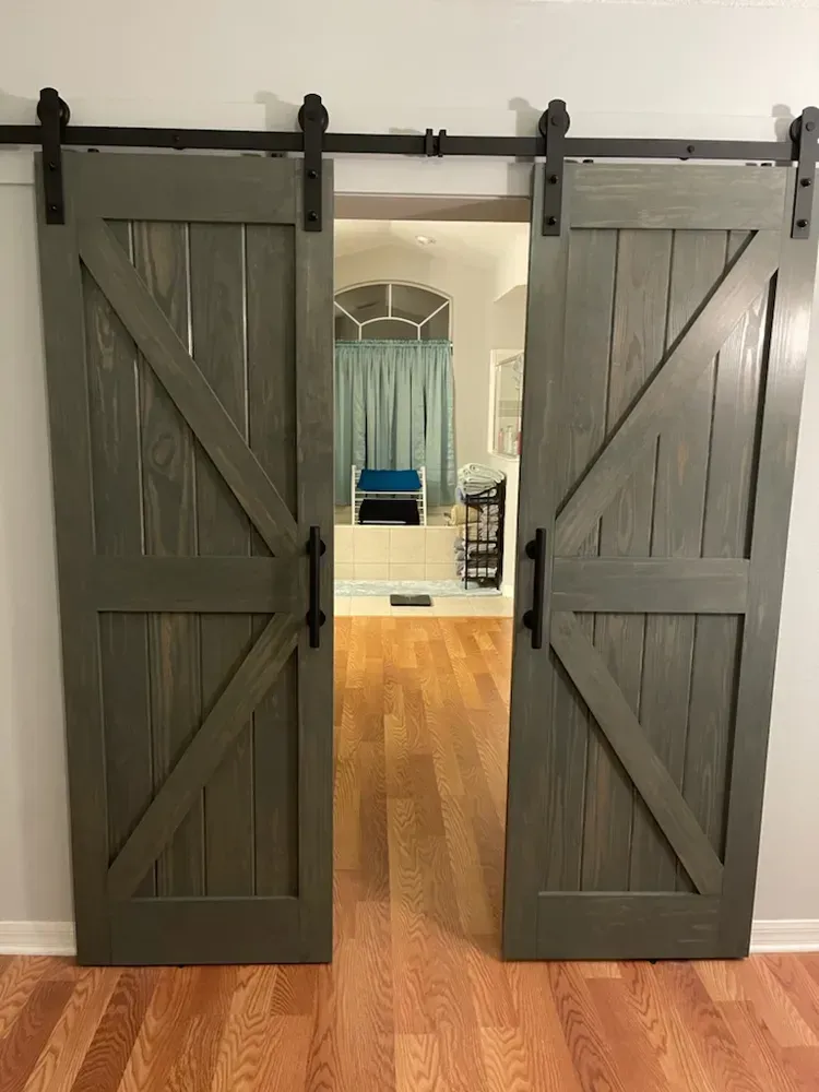 A pair of gray sliding barn doors are open to a living room.