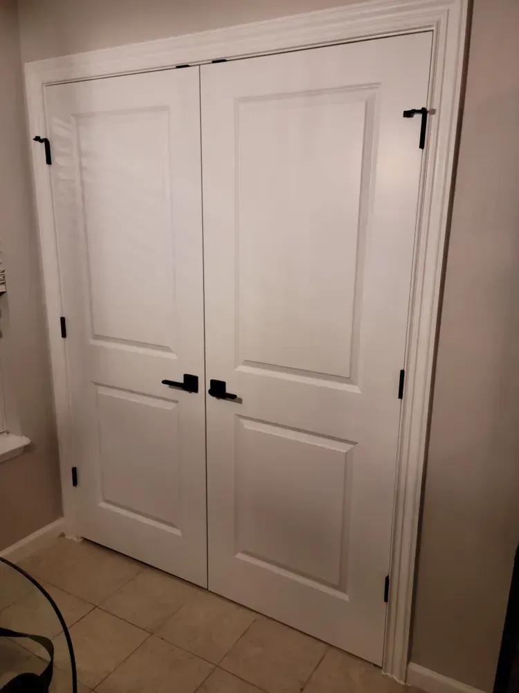 A pair of white double doors with black handles in a room.