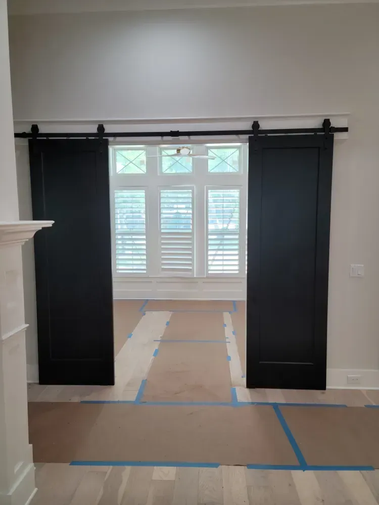 A pair of black sliding barn doors leading to a living room.