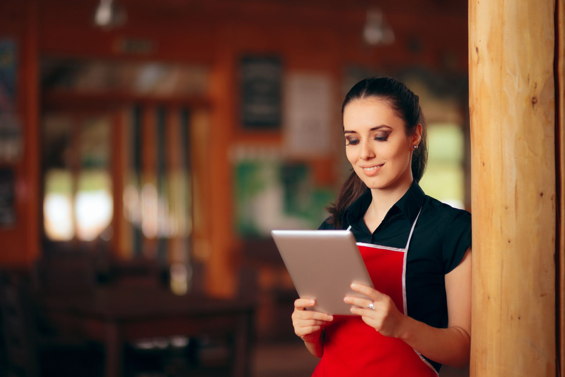 A waitress is using a tablet computer in a restaurant.