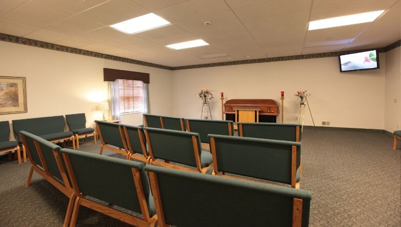 A room with rows of chairs and a television on the wall