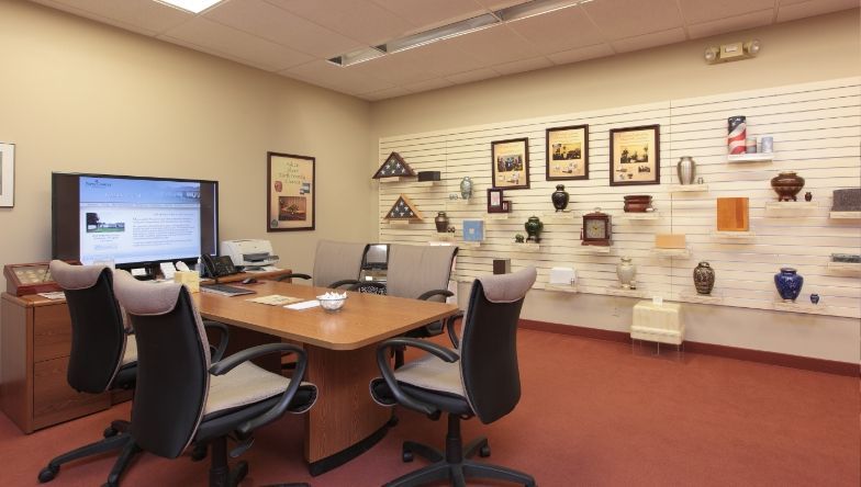 A conference room with a table and chairs and a television.