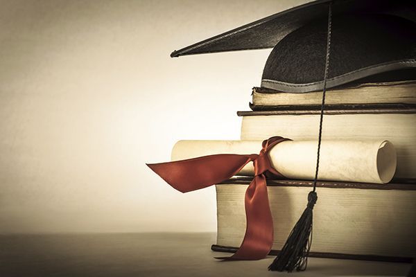 a graduation cap and diploma are sitting on top of a stack of books .