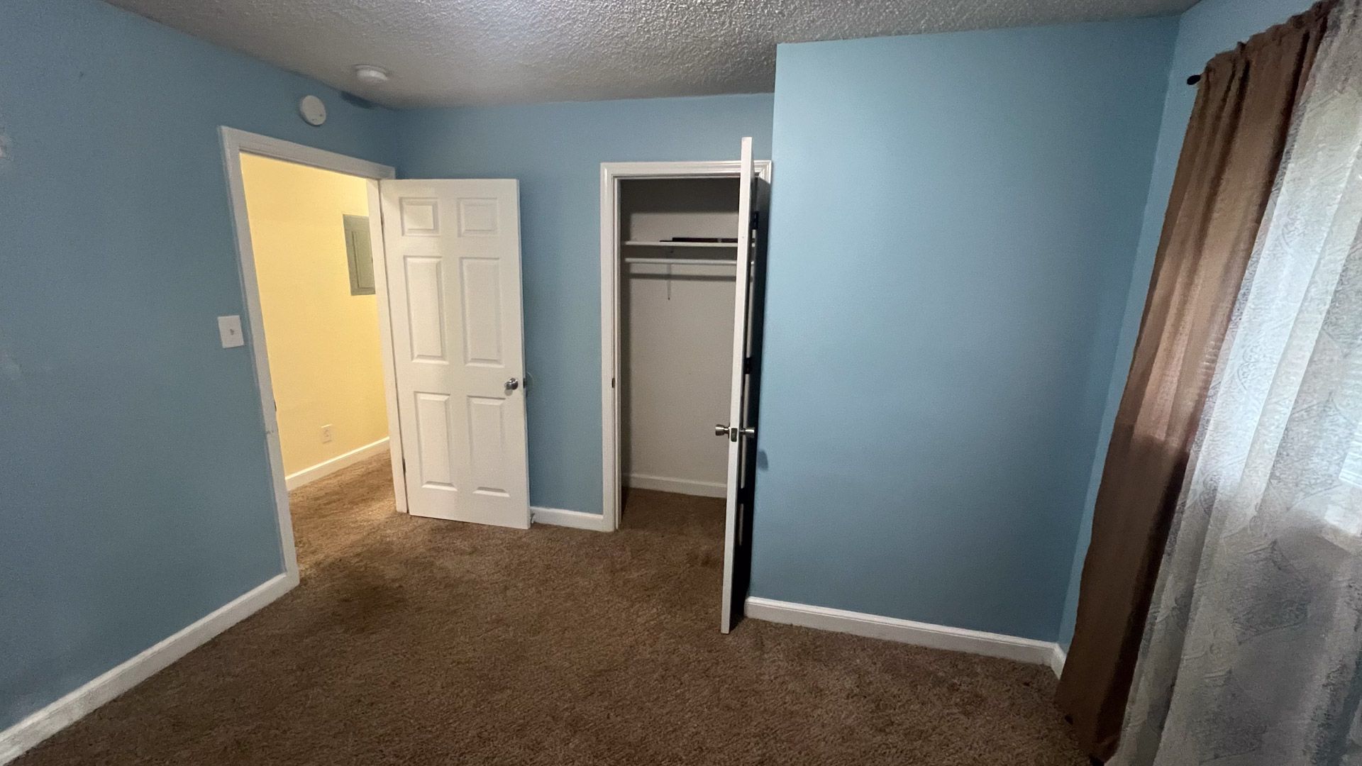An empty bedroom with blue walls and a closet.