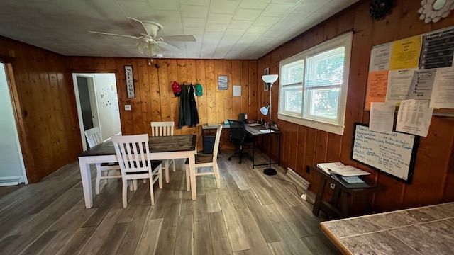 A dining room with wood paneling, a table and chairs, and a desk by a window.
