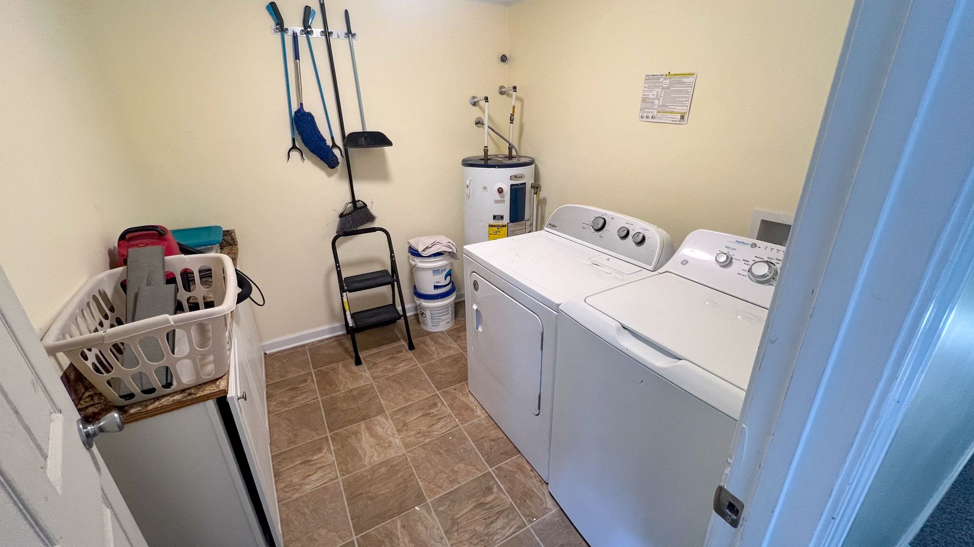 A laundry room with a washer and dryer and a basket.