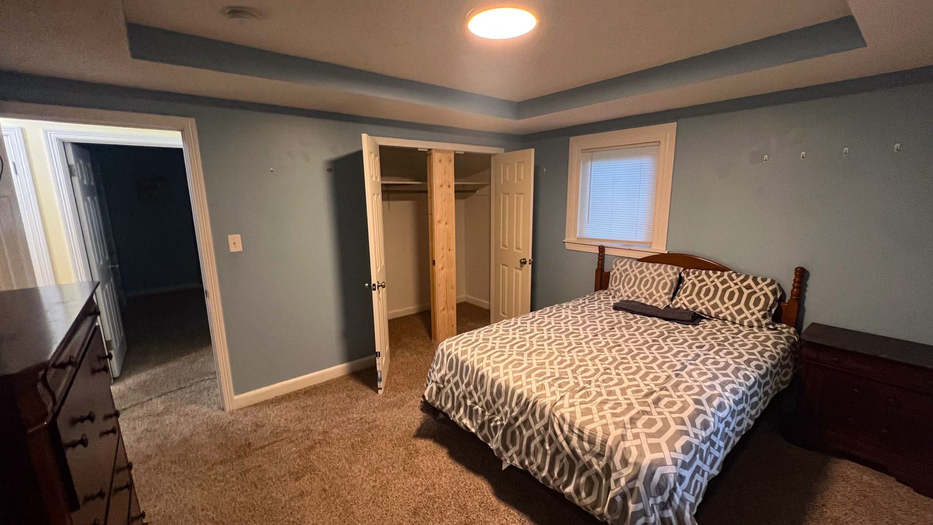 A bedroom with a bed , dresser , nightstand and closet.