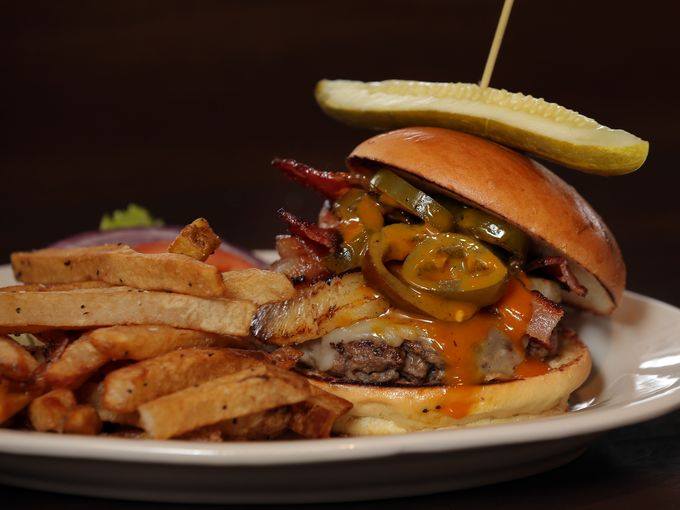 A hamburger and french fries on a plate with a pickle on top.