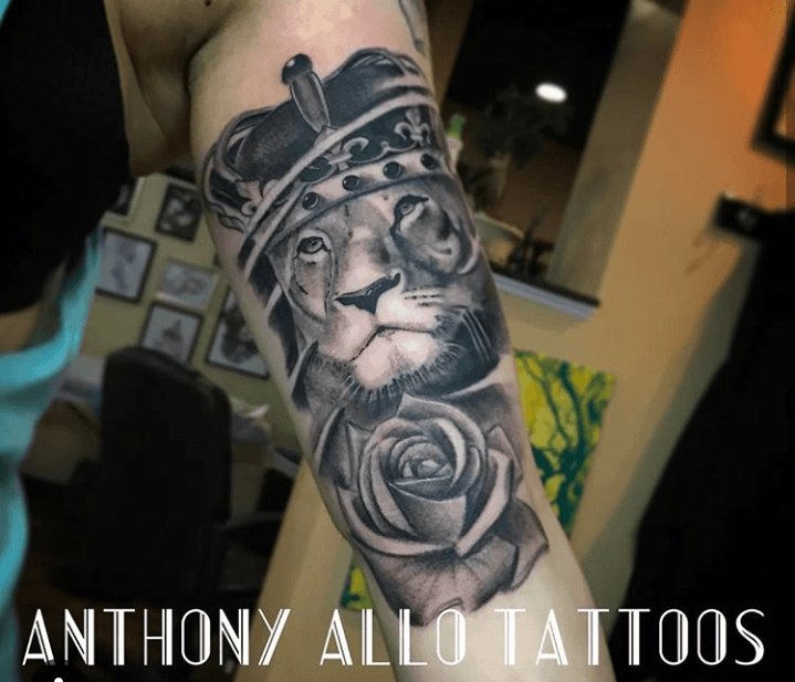 A tattoo of a lion wearing a crown and a rose by anthony allo tattoos