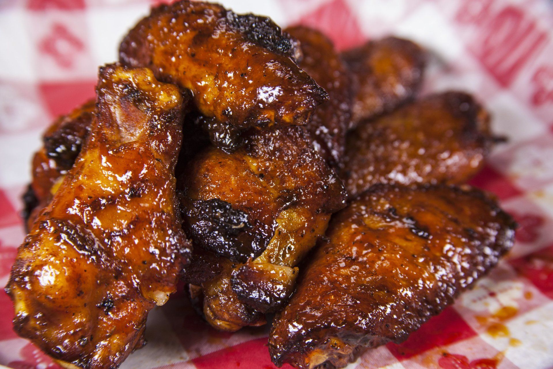 a close up of a plate of chicken wings on a red and white checkered napkin .