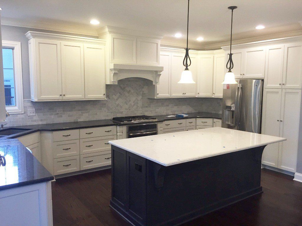 A kitchen with white cabinets and a black island