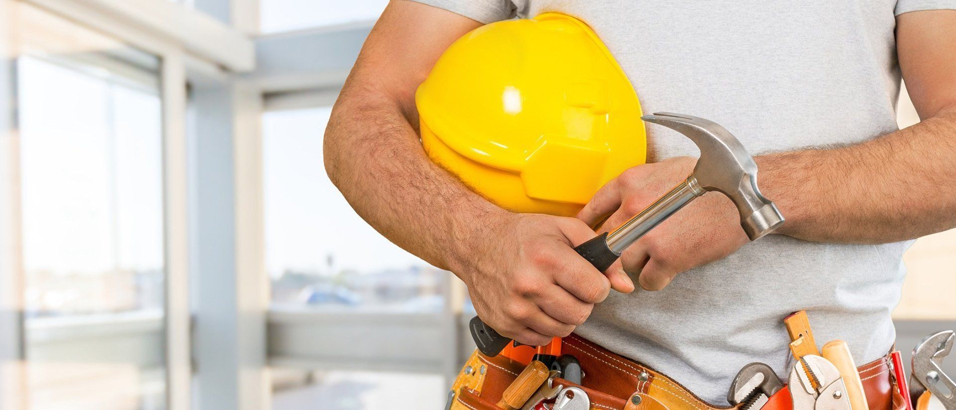 A man is holding a hard hat and a hammer.