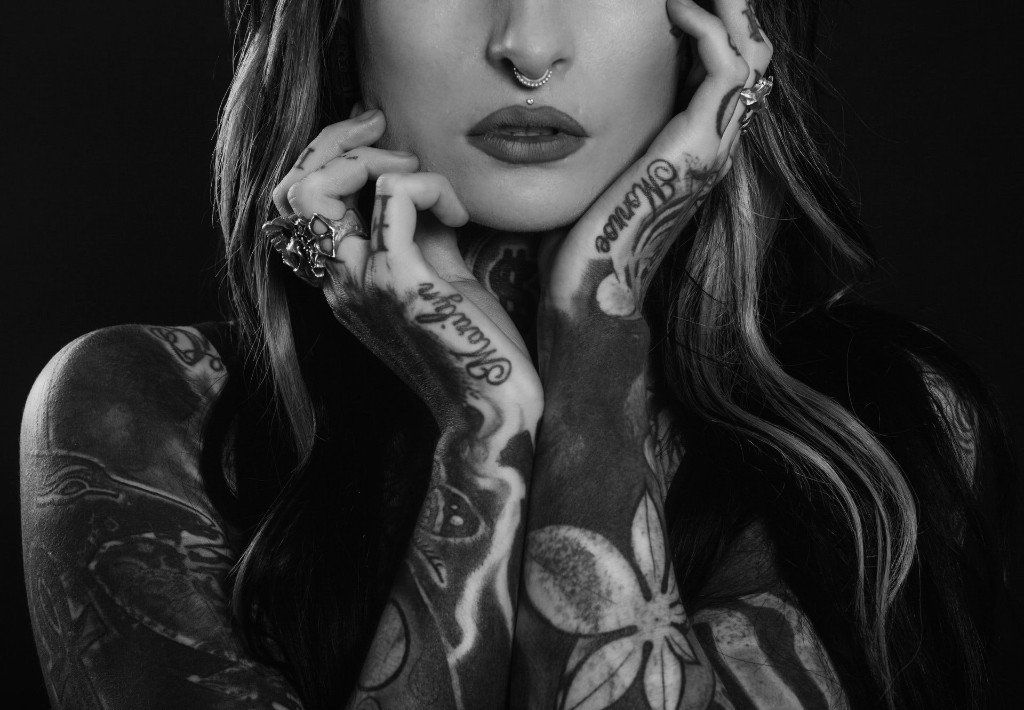 A black and white photo of a woman with tattoos on her arms.