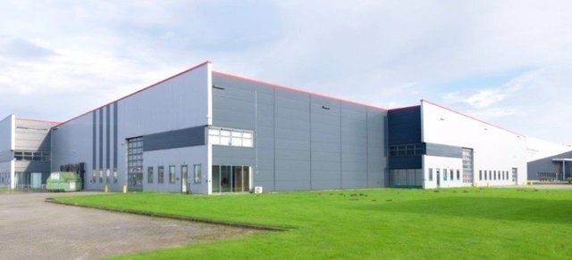 A large building with a lot of windows is sitting on top of a lush green field.