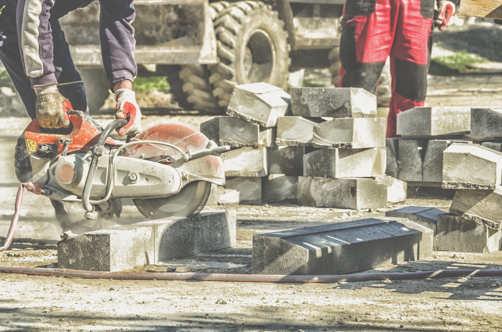 A man is using a circular saw to cut bricks on a construction site.