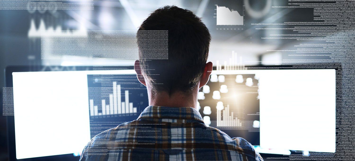 A man is looking at a computer screen with a lot of data on it.