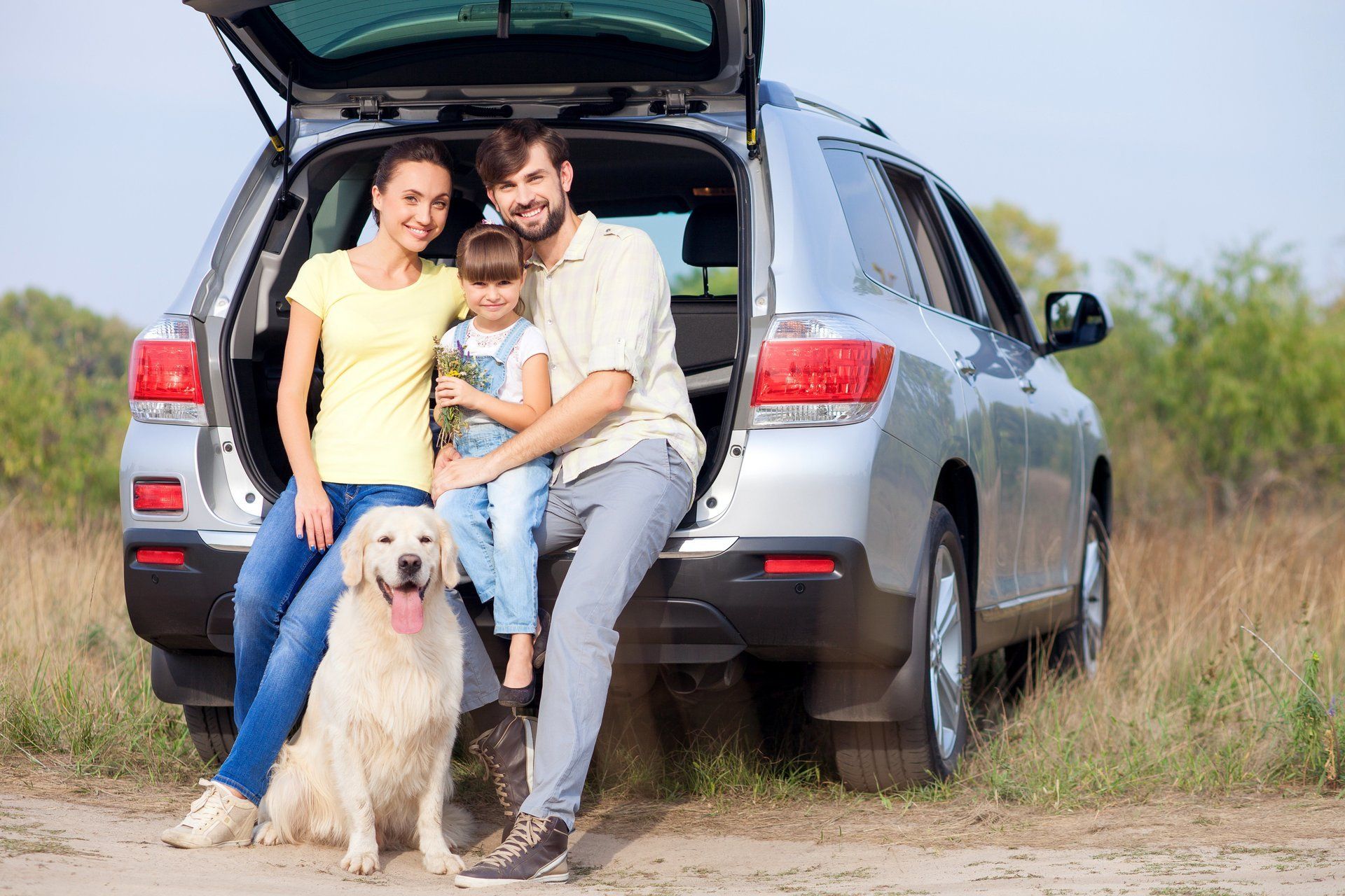 A family and their dog are sitting in the back of a car.