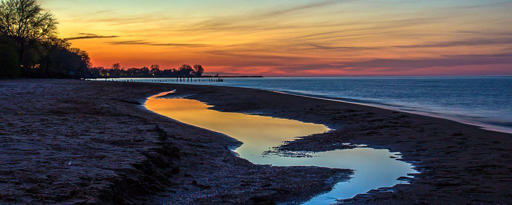 A river running through a rocky beach at sunset.