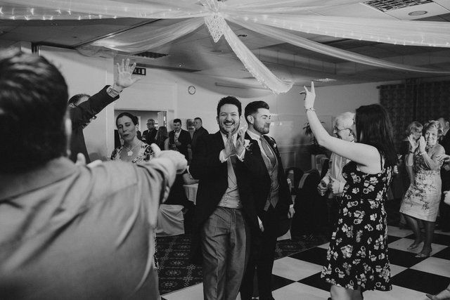 A black and white photo of a group of people dancing at a wedding reception.