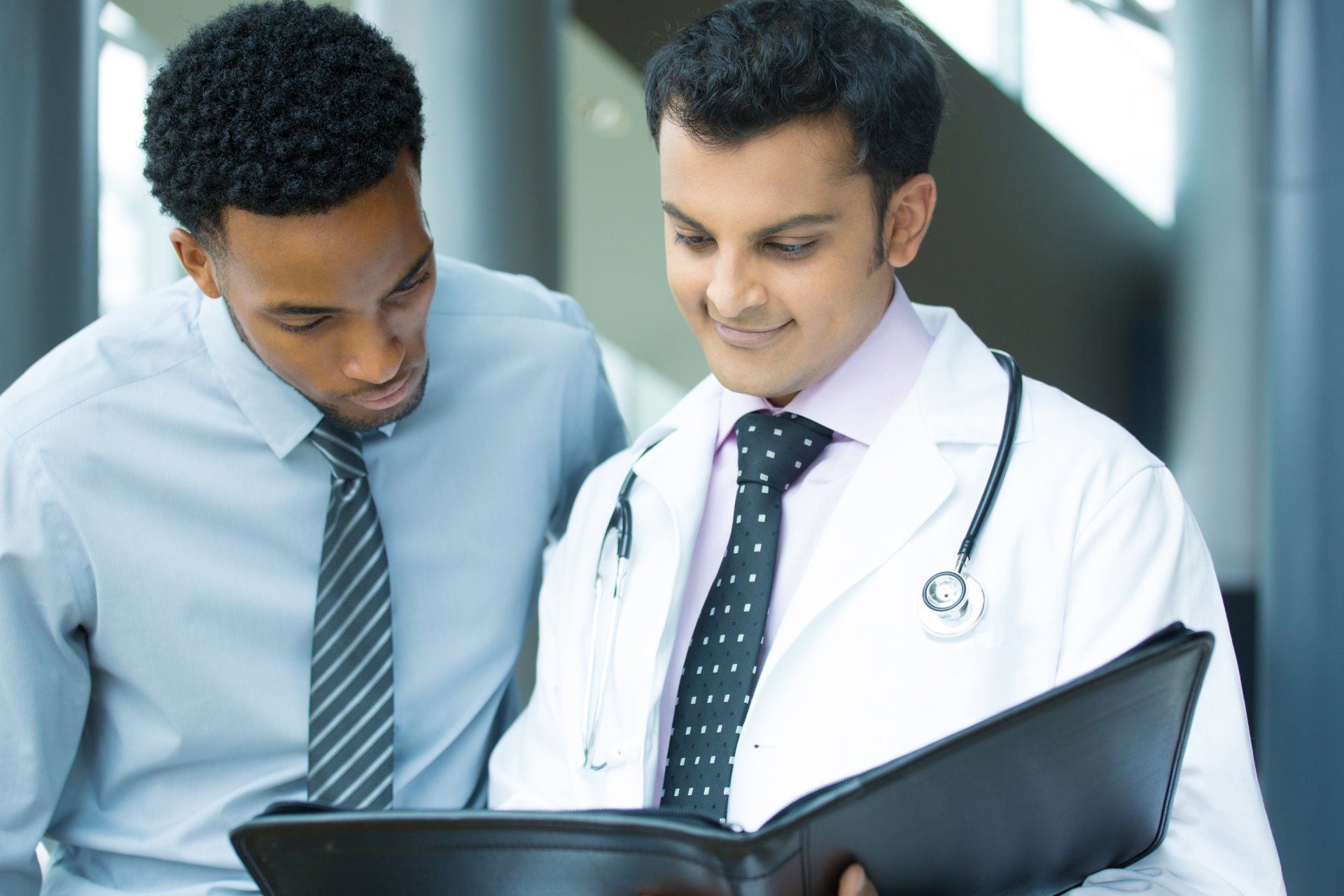 A doctor and a businessman are looking at a clipboard