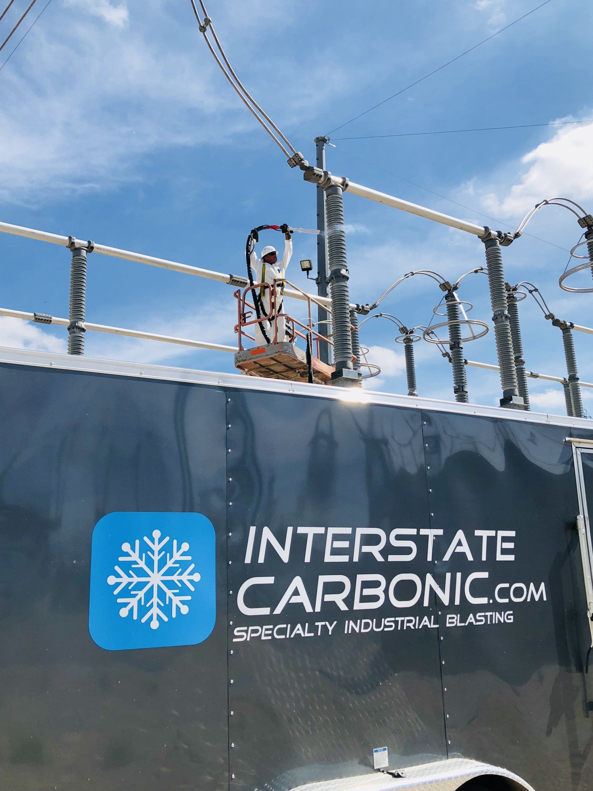 A man is standing on top of a trailer that says interstate carbonic.com