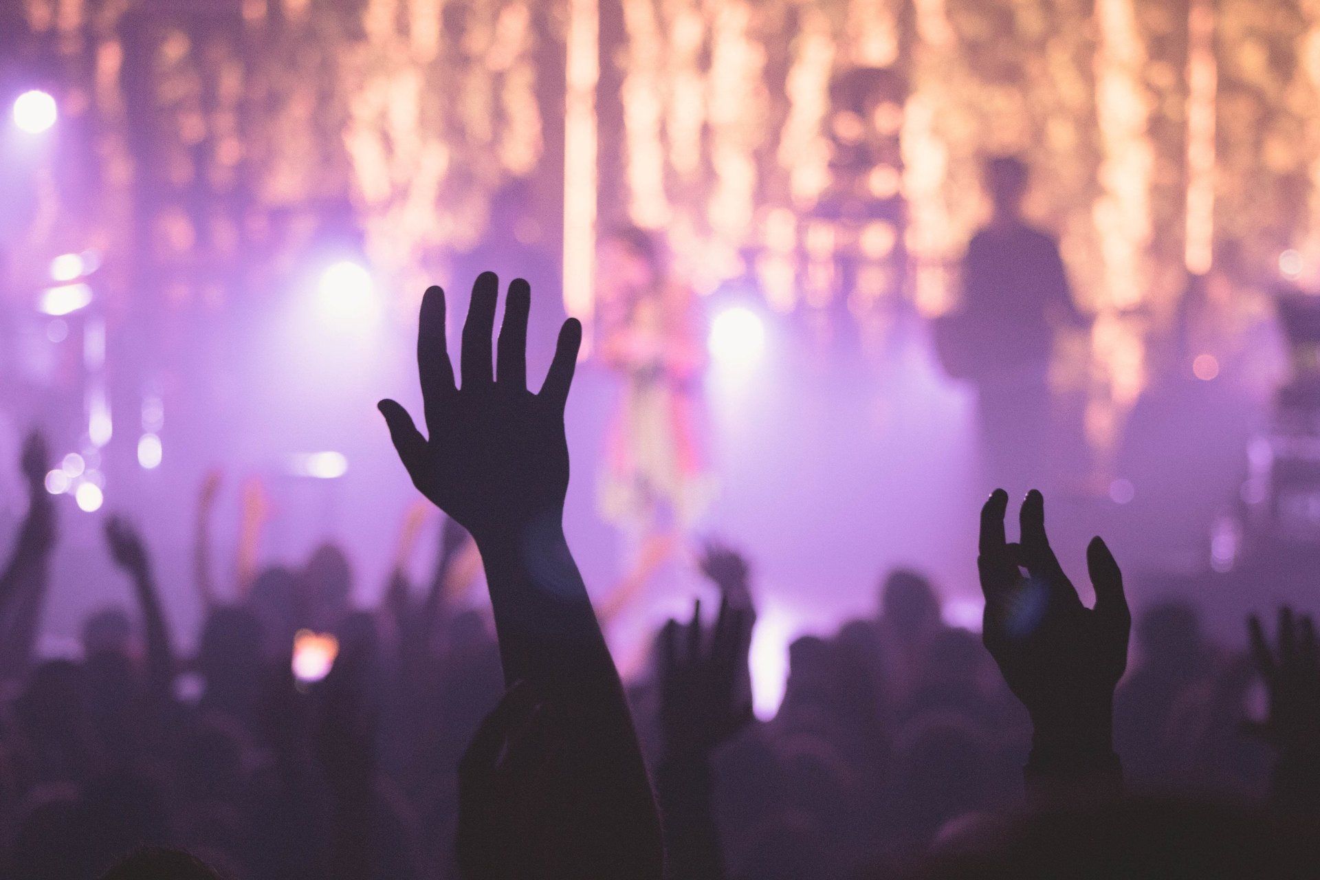 A crowd of people are raising their hands in the air at a concert.