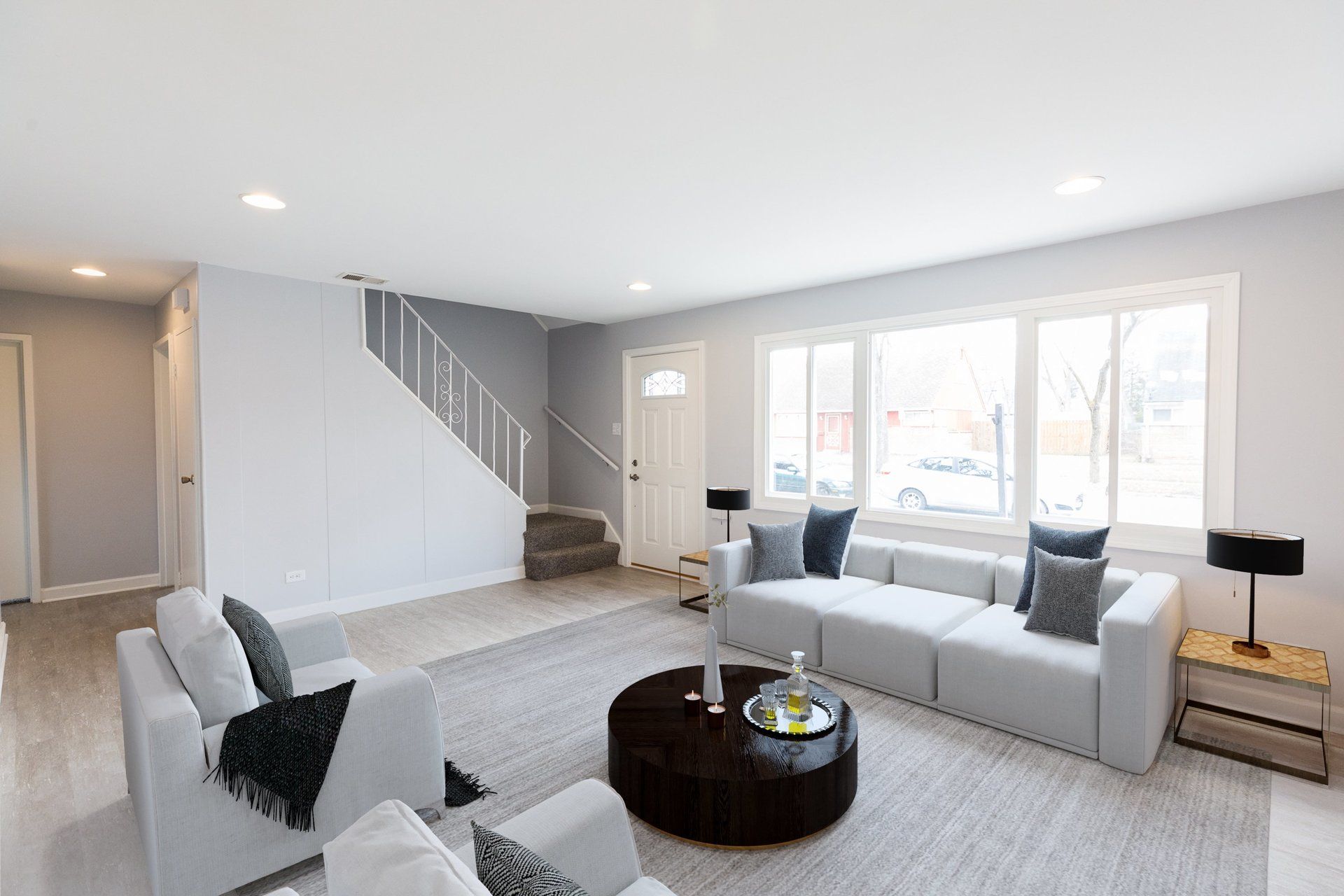 A living room with a couch , chairs , coffee table and stairs.