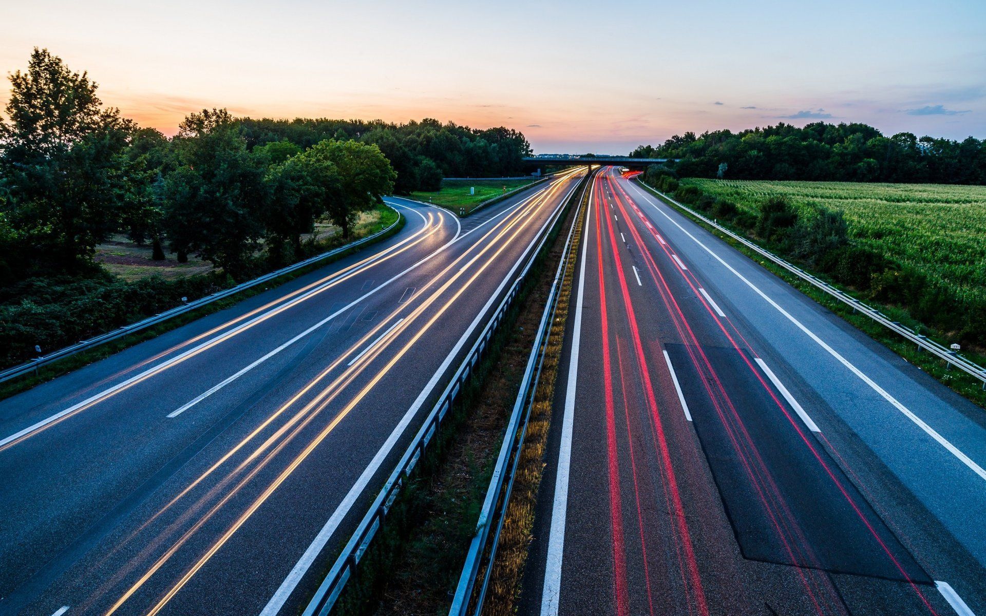 An aerial view of a highway at sunset with cars driving down it.