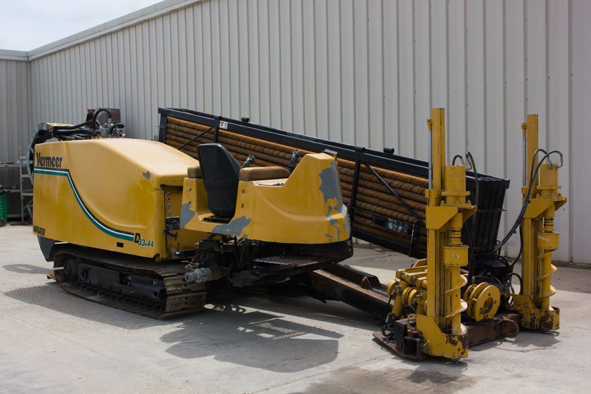 A yellow machine is parked in front of a building.