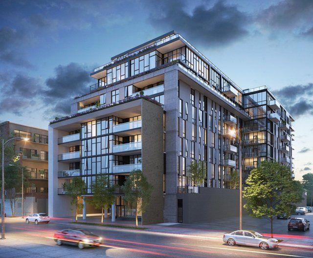 A large building with a lot of windows is sitting on the corner of a city street.