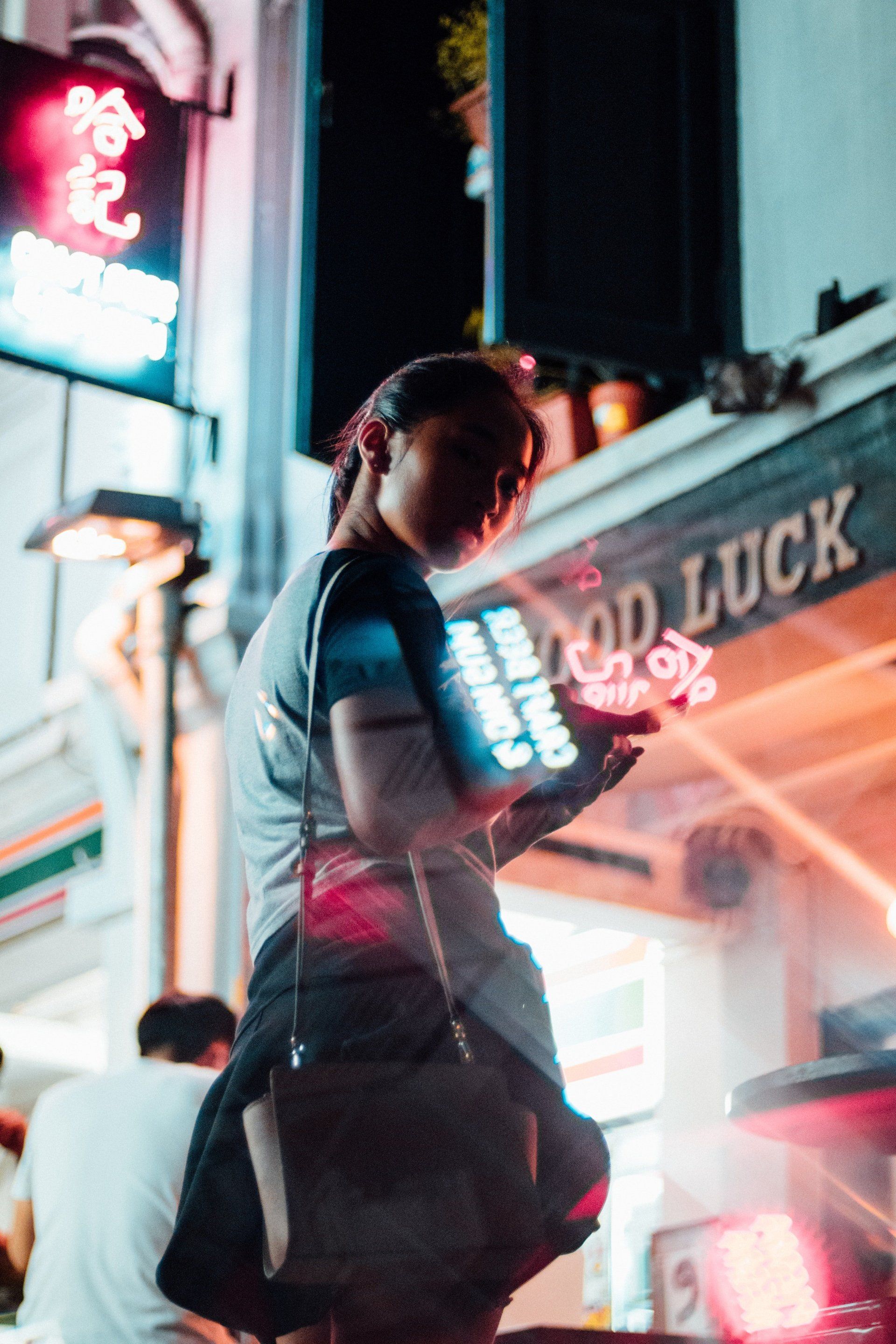 A woman is standing in front of a building with a sign that says good luck.