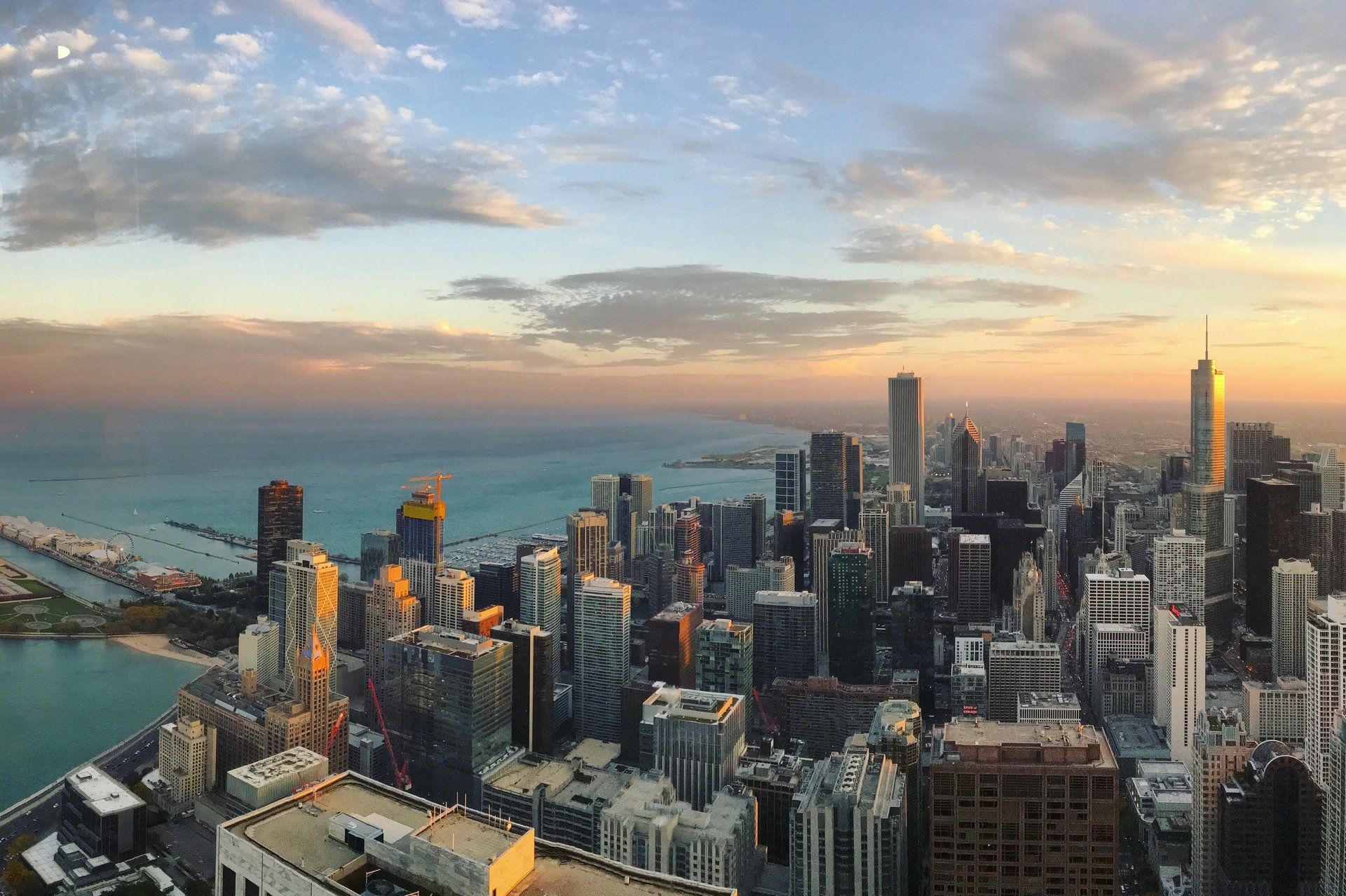 An aerial view of a city skyline at sunset with a body of water in the foreground.