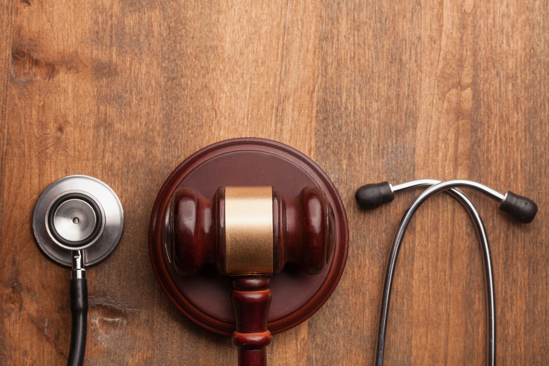 A stethoscope , judge 's gavel and a hammer are on a wooden table.