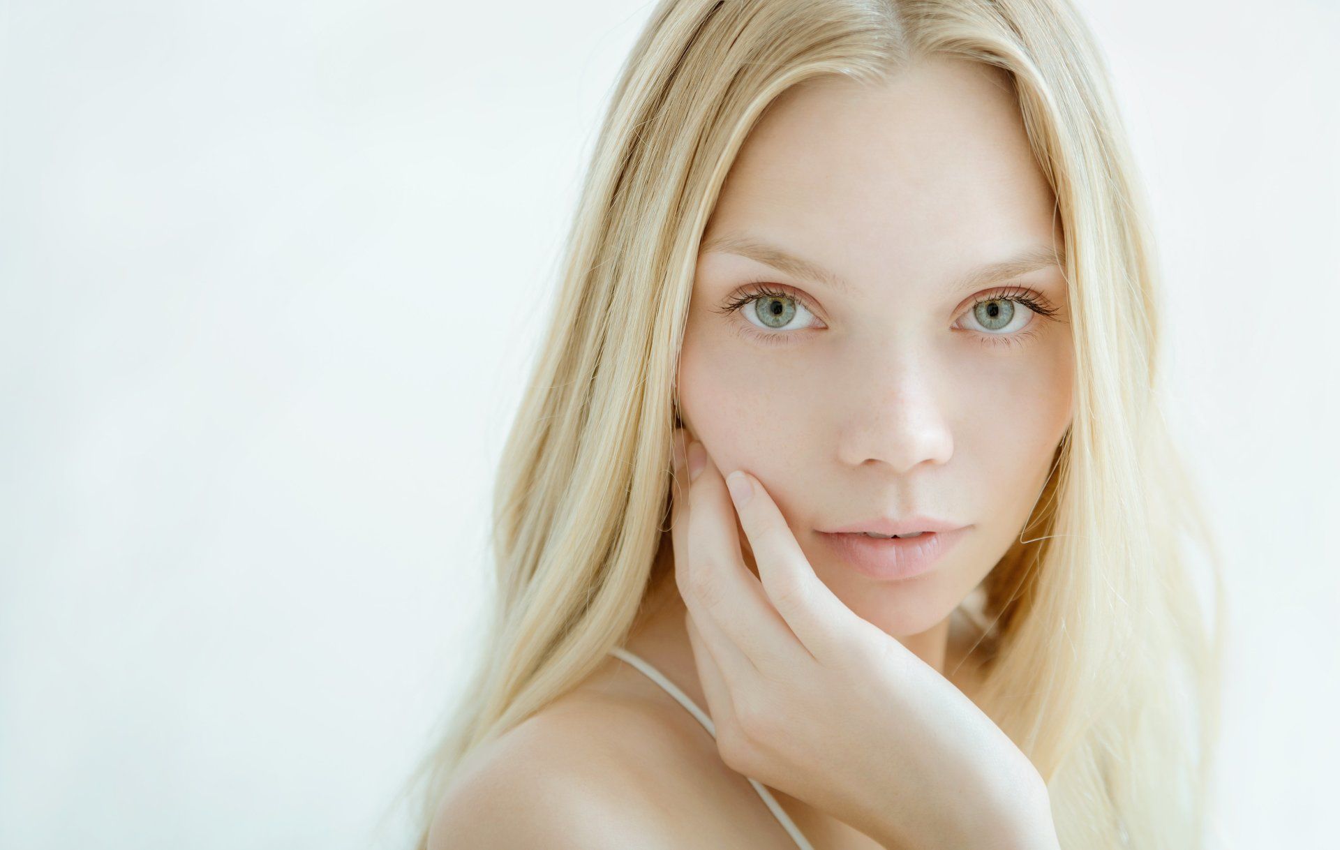 A close up of a woman 's face with her hand on her face.