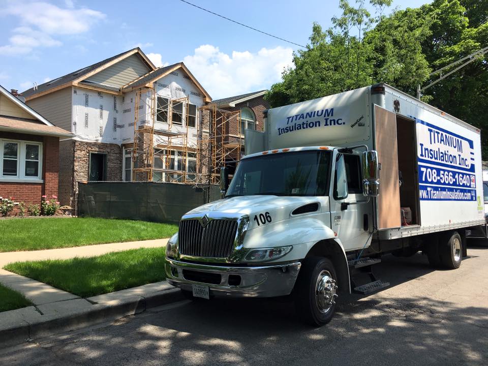 A white truck is parked in front of a house under construction.
