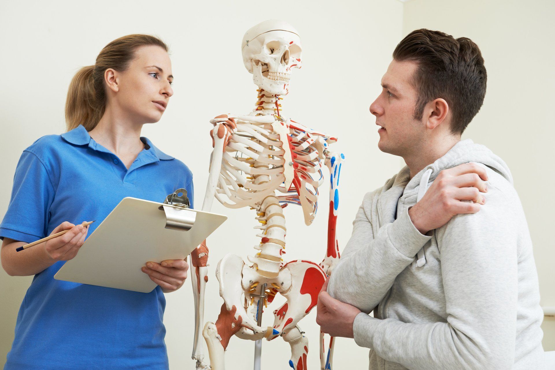 A woman is talking to a man in front of a skeleton.