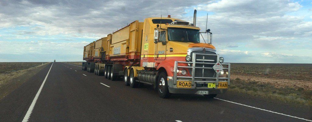 A yellow and red semi truck is driving down a highway.