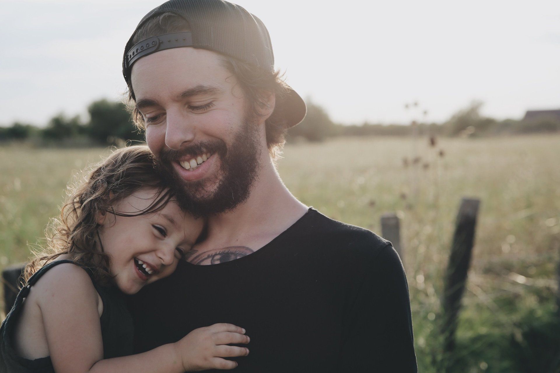 A man with a beard is holding a little girl in his arms.