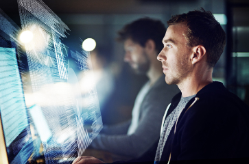A man is looking at a computer screen in a dark room.