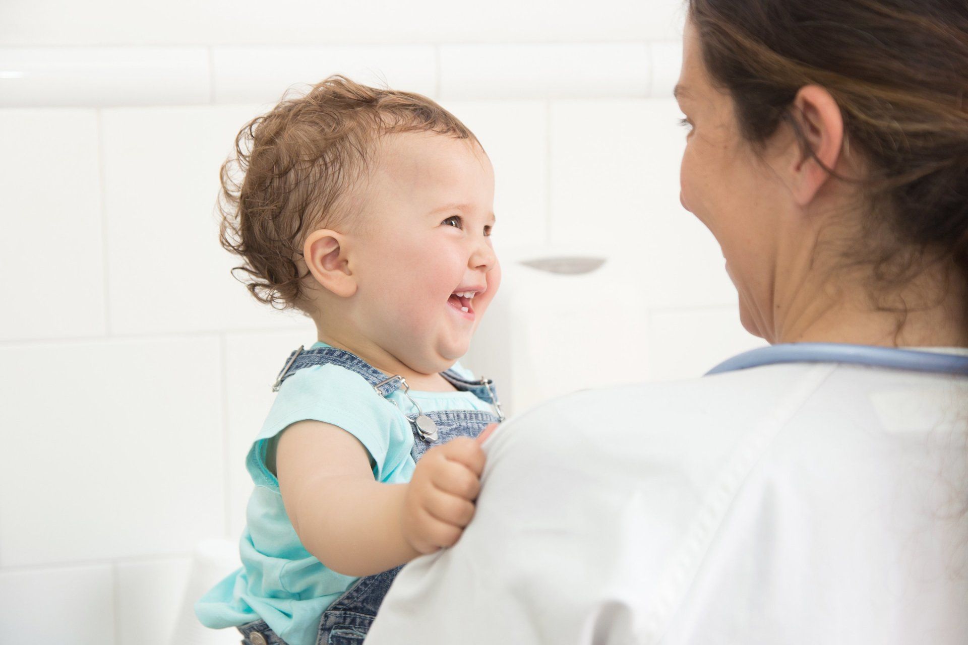 A doctor is holding a baby in her arms and the baby is smiling at the doctor.
