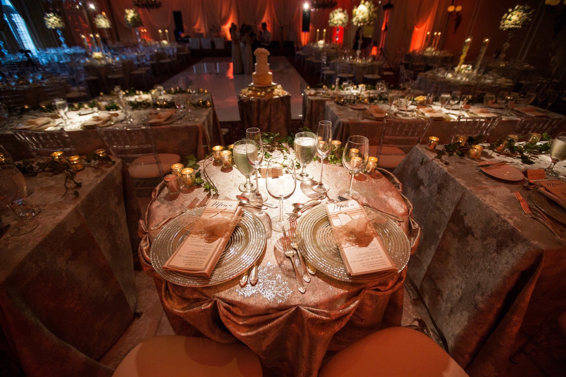A table set for a wedding reception with plates , candles , and silverware.