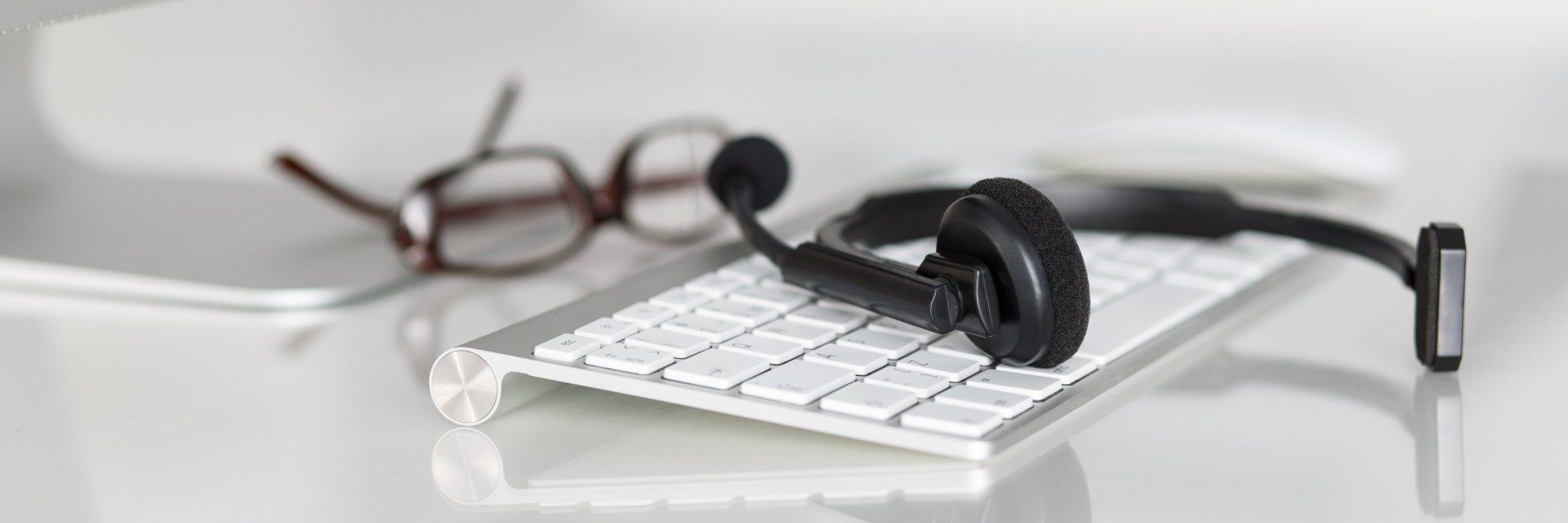 a pair of glasses and a headset are sitting on top of a computer keyboard .
