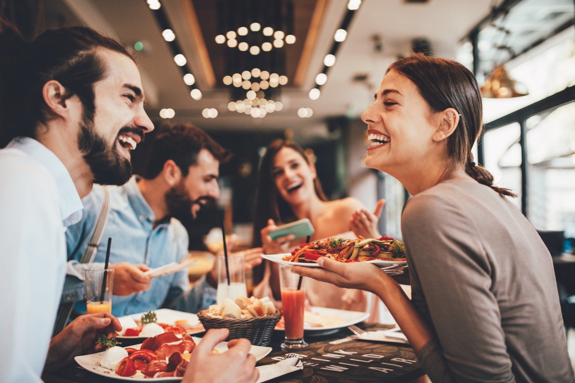 A group of people are sitting at a table in a restaurant eating food.