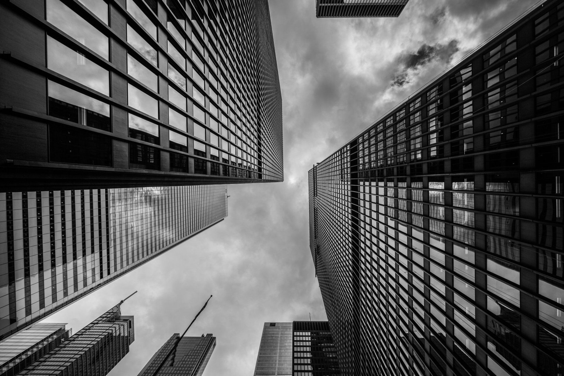 Looking up at a black and white photo of tall buildings in a city.